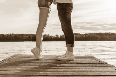 Low section of man standing on pier over lake