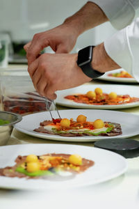 Cropped hand of person preparing food on table