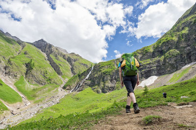 Rear view of woman walking on mountain against sky