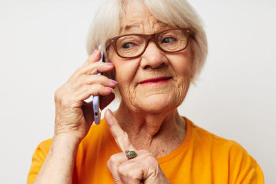 Smiling senior woman talking on phone against white background