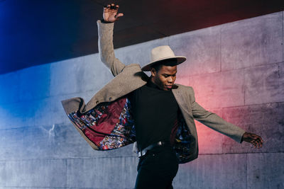 Full length of man wearing hat standing against wall