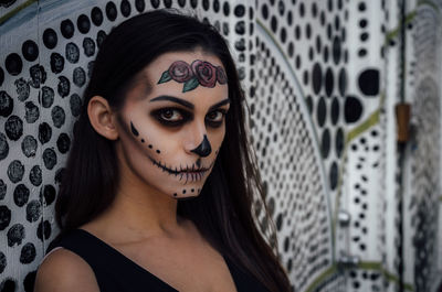 Close-up portrait of woman with spooky halloween make-up against wall