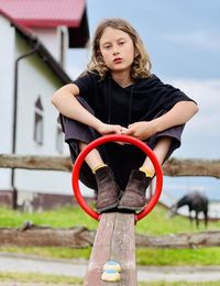 Portrait of young woman sitting on railing