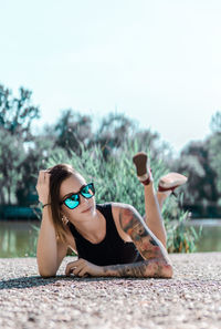 Portrait of young woman lying on sunglasses