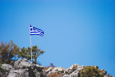 Low angle view of greece flag against clear blue sky