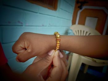 Cropped hand of girl tying rakhi to brother