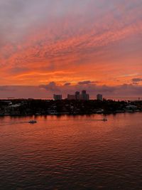 Scenic view of sea by buildings against sky during sunset