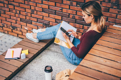 Young woman reading book while sitting on table