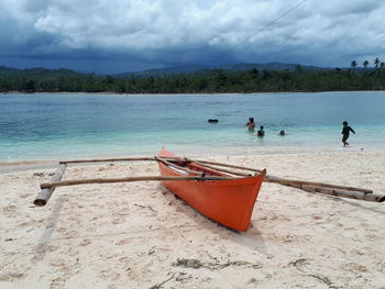 Boat moored on beach against sky