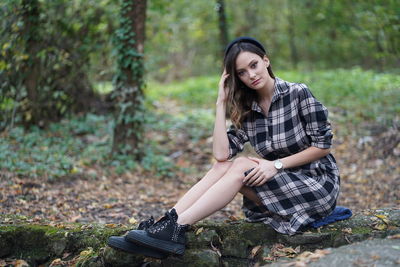 Portrait of young woman sitting on land in forest