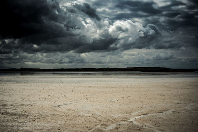 Scenic view of beach against storm clouds