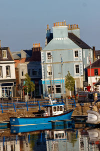 Sailboats moored on canal by buildings in city against clear sky