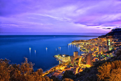 High angle view of cityscape by sea at dusk