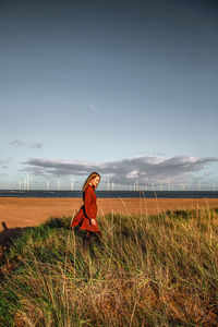 Full length of woman standing on field against sky