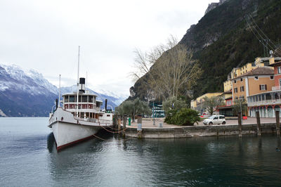 Boats moored on river by mountain against sky