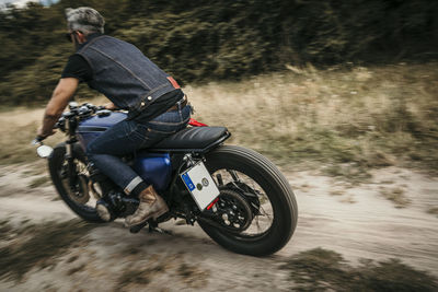 Mature biker riding motorcycle on dirt road