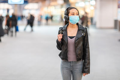 Woman wearing mask looking away while standing outdoors