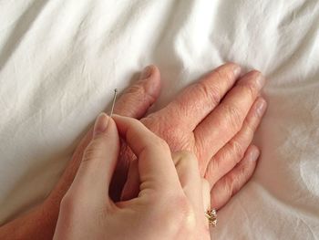 Close-up of woman giving acupuncture to customer on bed