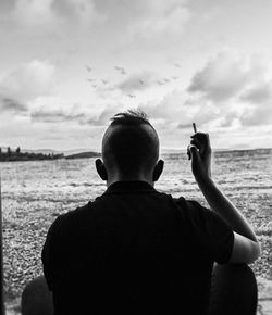 Rear view of man on beach against sky