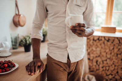 Midsection of man holding ice cream standing on table