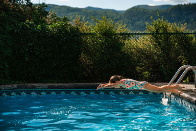 5 years old girl trying to dive in a swimming pool during summer