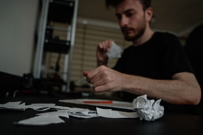 Man trying to write something,wads of paper, struggling with writer's block.