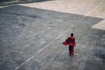 Full length rear view of monk standing on footpath