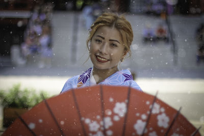 Portrait of smiling woman in kimono standing outdoors