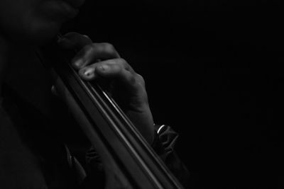 Close-up of man playing string instrument against black background
