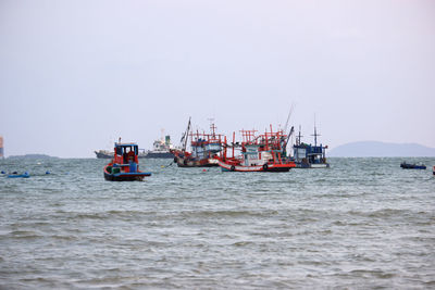 Fishing boats sailing in sea against clear sky