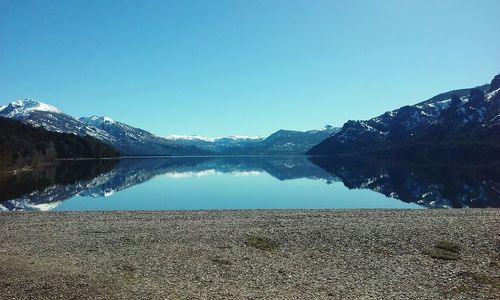 Scenic view of lake and mountains against clear blue sky