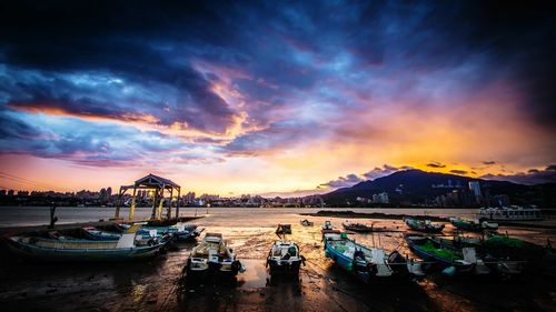 Boats moored at harbor against sky during sunset