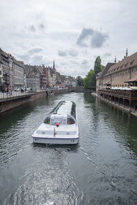 View of boats in river against cloudy sky