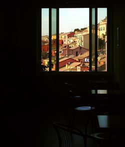 Buildings in city against sky seen through window