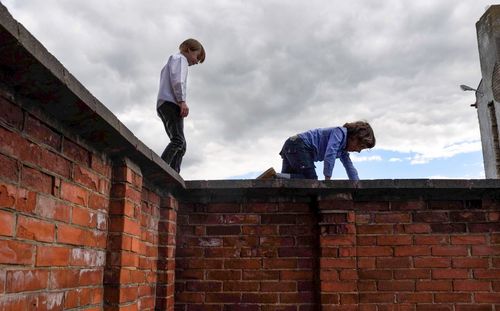 Low angle view of man standing against brick wall