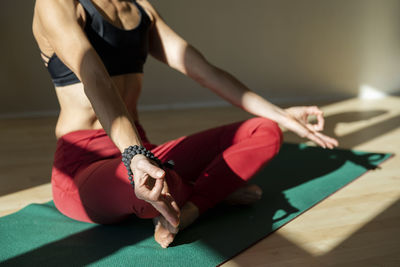 Mature woman doing sukasana meditating pose on exercise mat at home