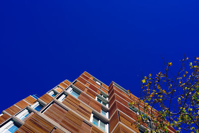 Low angle view of apartment building against clear blue sky