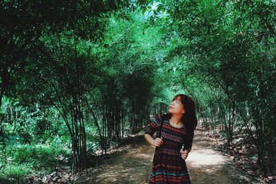 Portrait of a smiling young woman standing in forest