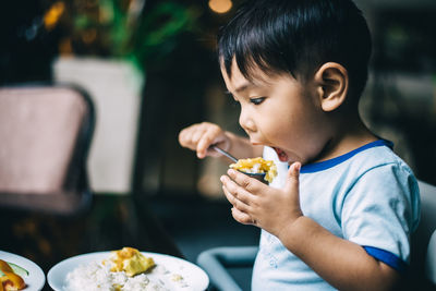 Cute boy eating food at home