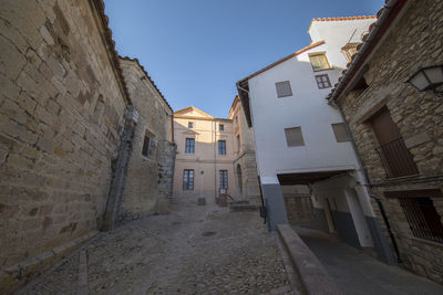 Narrow street amidst buildings in town against clear sky