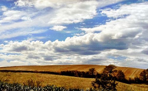 Scenic view of field against cloudy sky