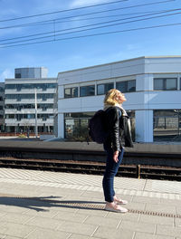 Rear view of woman standing against buildings in city