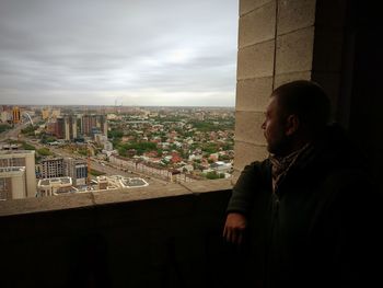 Man looking at city buildings against sky
