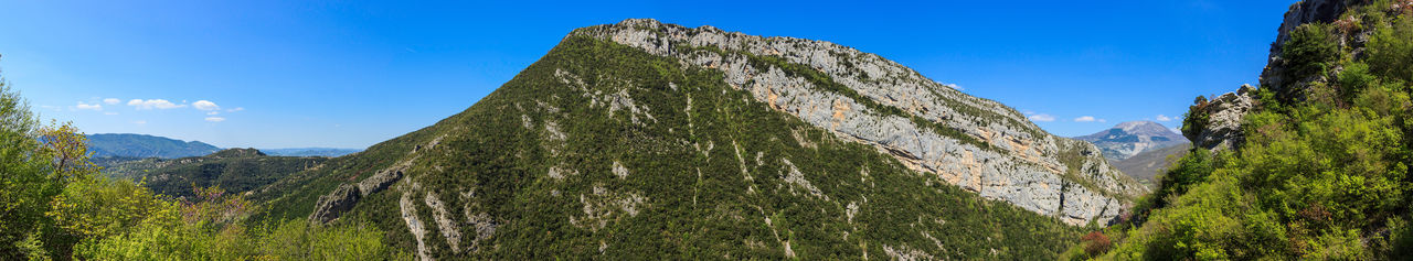 Low angle view of rocky mountain against blue sky