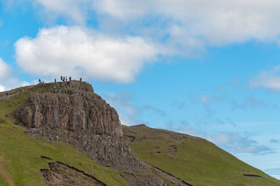 Unrecognizable group of tourists at the top of old man of storr rock wall, isle of skye, scotland