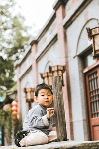Boy sitting in front of building