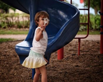 Girl holding magic wand while standing by slide on playground