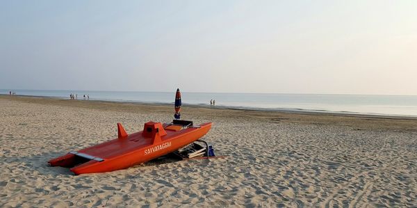 Deck chairs on beach against sky