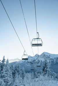 Overhead cable car on snowcapped mountains against sky