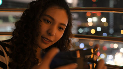 Close-up of smiling young woman in city at night